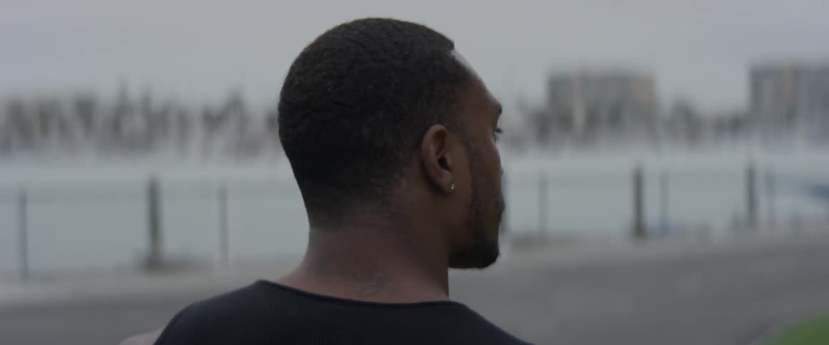 Man walks towards water with city in background