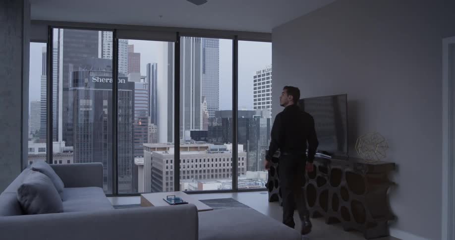 A man walks into a room and toward large windows