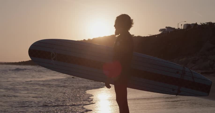 A man that is holding a surfboard next to the ocean