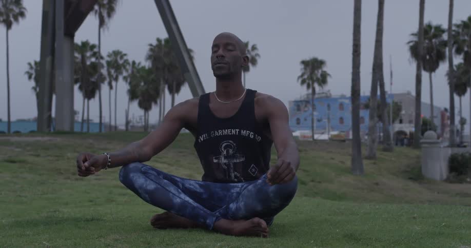 A man sitting in the grass with his legs crossed and eyes closed