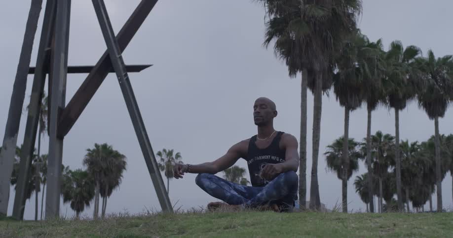 A man sitting in the grass in a meditation pose