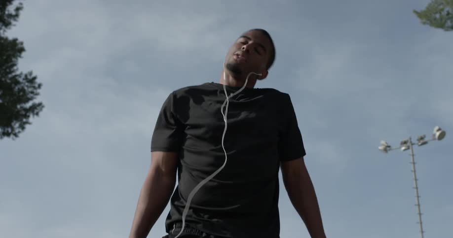 A man hops up and down as he wears headphones