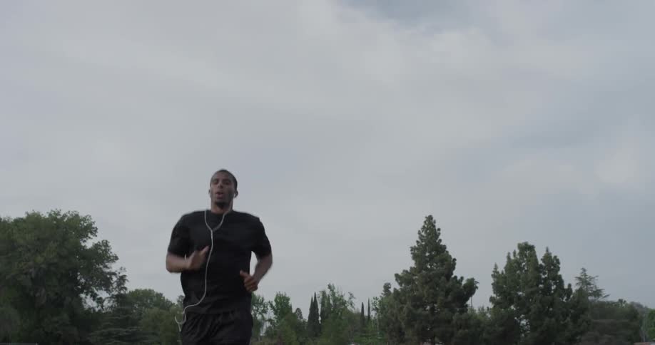 A man jogging down the street wearing headphones