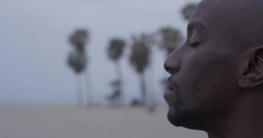 A man has his eyes closed on the beach