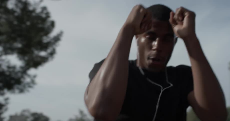 A man wearing earbuds practices boxing outside