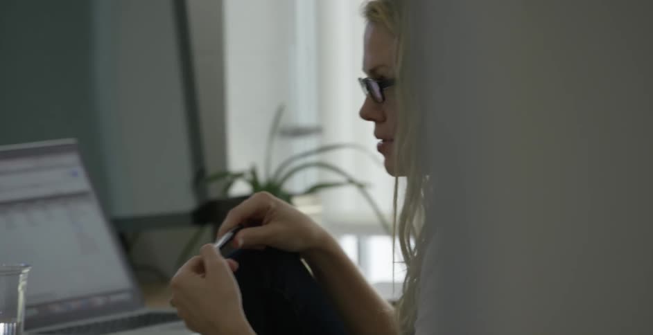 Woman is sitting down next to her desk and laptop on it