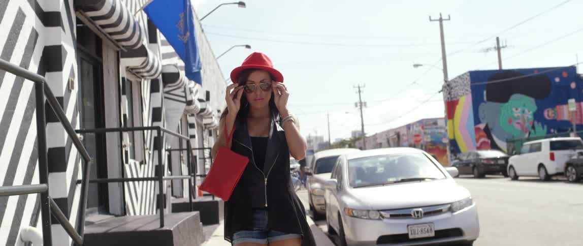 Modern woman putting on her sunglasses while walking down a chic city street