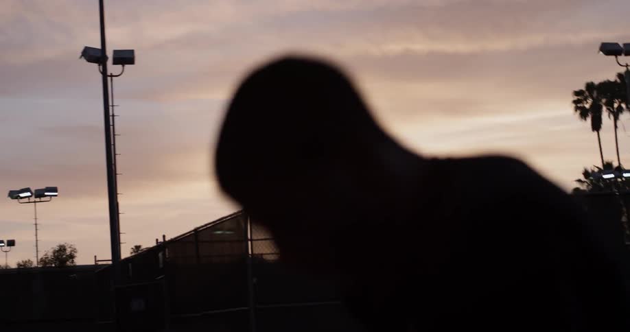 A man shadow boxes at dusk