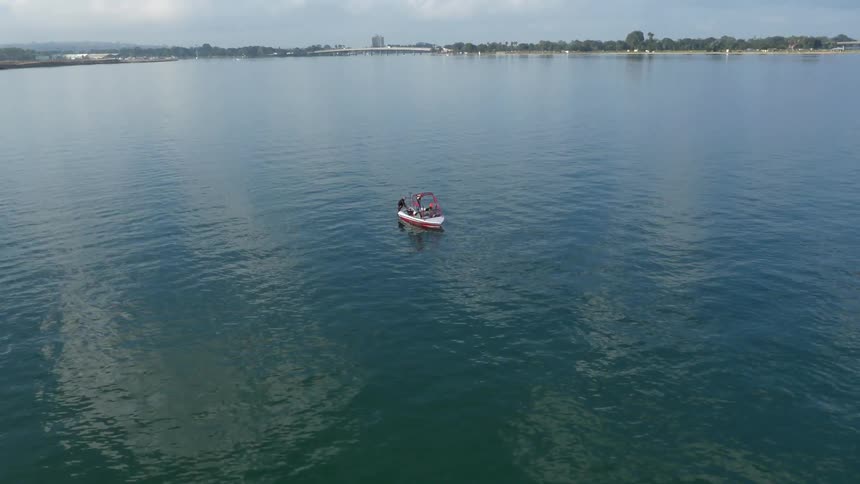 A boat floats in the middle of an otherwise empty lake