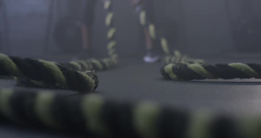 A person picks up two large ropes from the floor