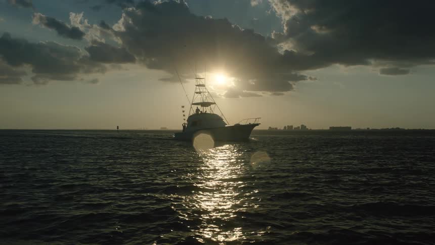 A boat floating on the ocean at sunset