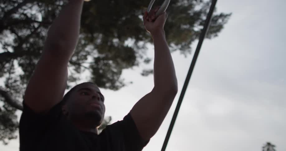 Man does pull ups on exercise equipment outdoors