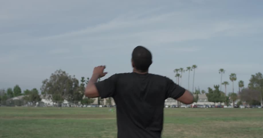 Man jogs across a large field in the city