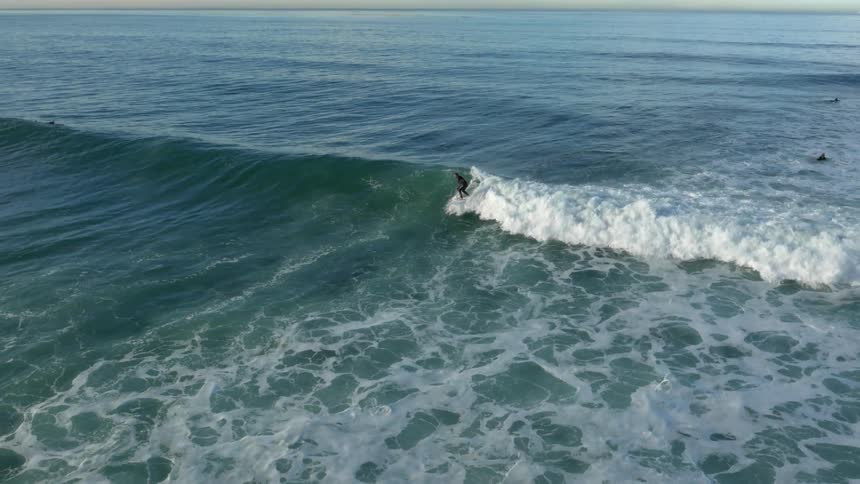 A surfer catching a wave as other surfers float and wait for a wave