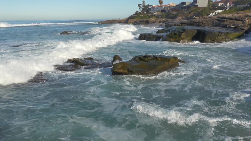 Waves crashing and foaming against boulders on a rocky shoreline