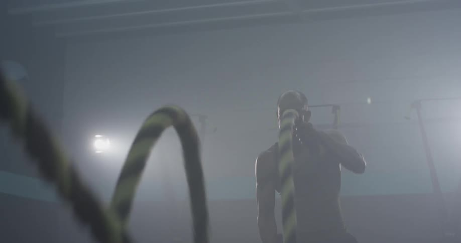 A man swinging ropes at a gym