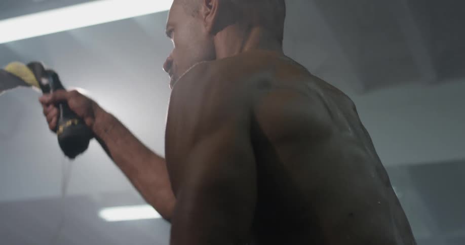 A man swinging ropes in a gym to work out