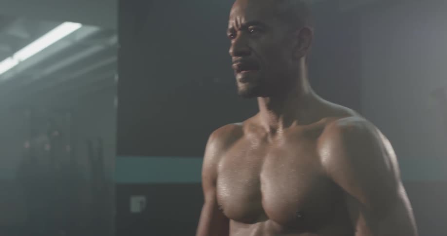 A man is in a gym with his shirt off