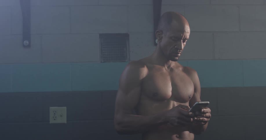 A man texting on a phone with no shirt on