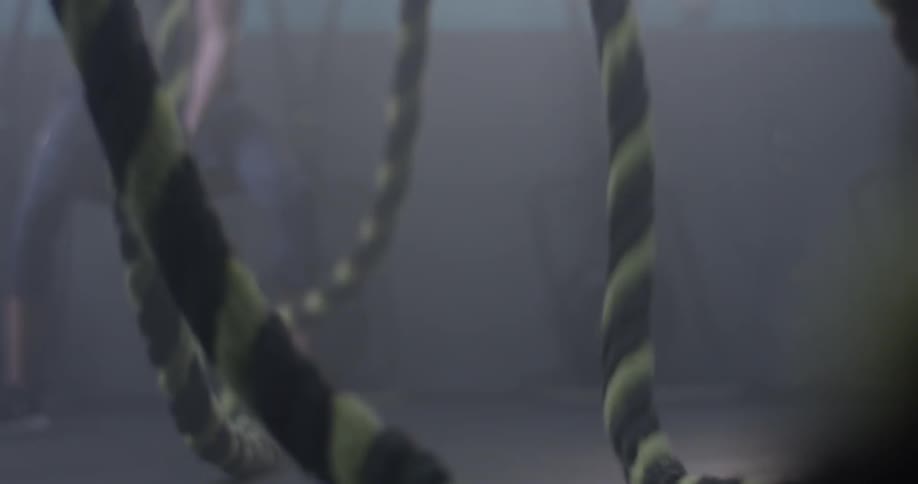 A man swinging ropes in a gym