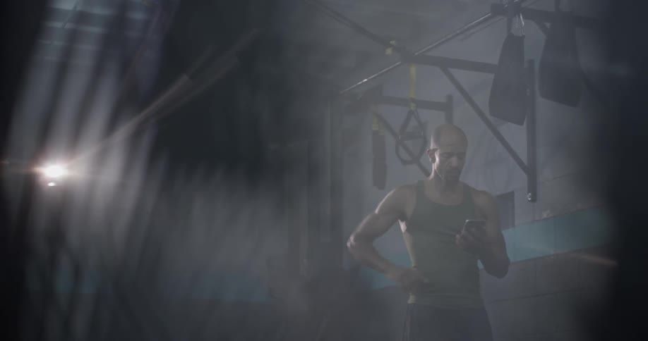 A man walking to pick up his phone in a gym