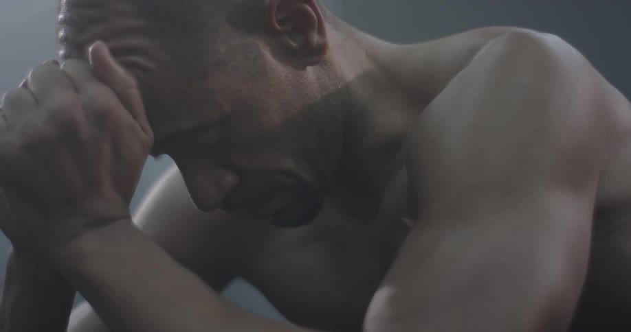 A man bent down with his face in his hands, stands up