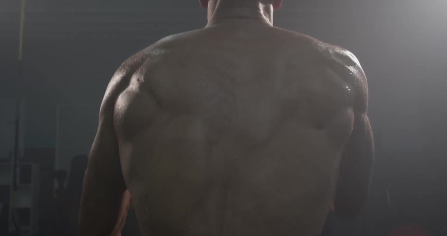 Shirtless man slams ropes on a gym floor