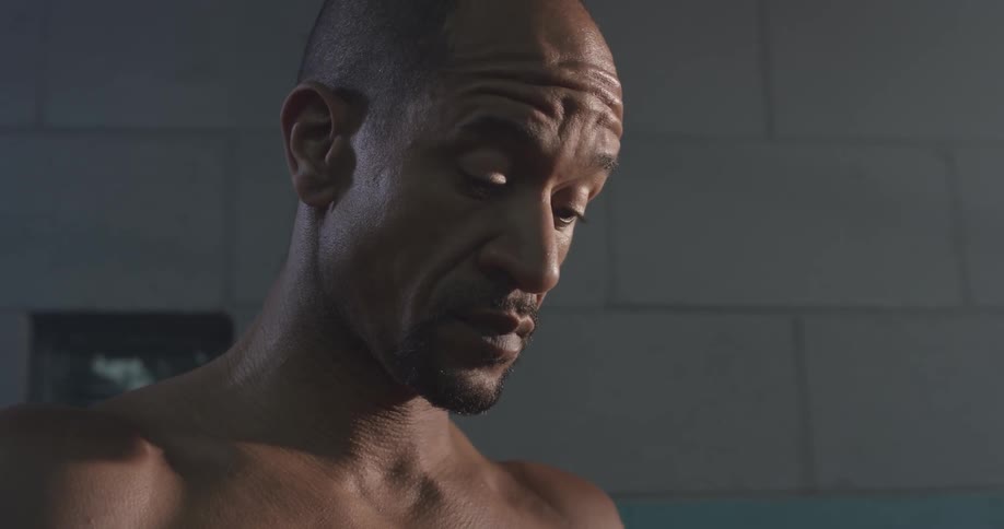 Shirtless man looks down and stretches neck