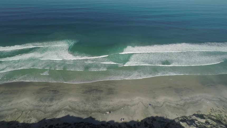 Aerial view of ocean waves washing onto a sandy beach