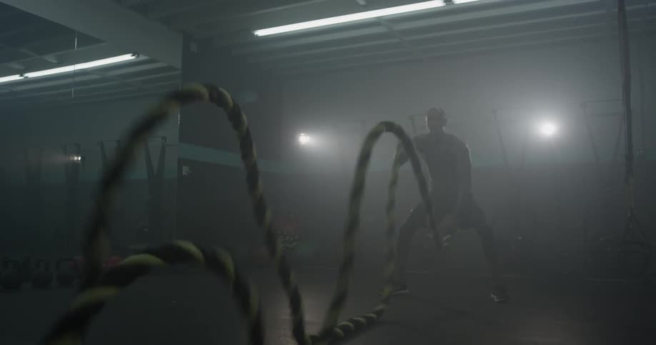 A man sends waves down two ropes by holding one end in each hand and waving it up and down