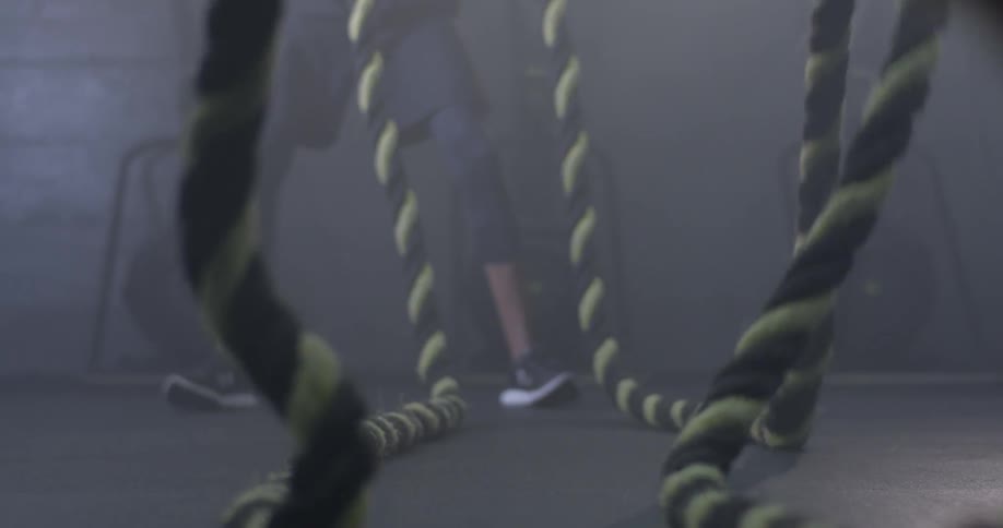 A man swinging ropes for a workout at a gym