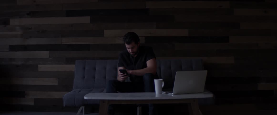 A man sitting on a couch looking at a cell phone