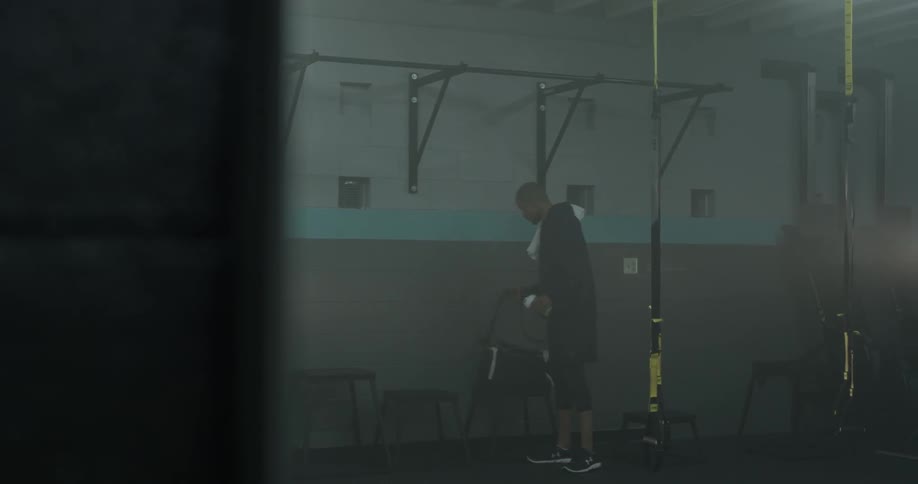 A man takes a drink and picks up items from a stool