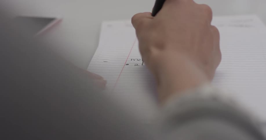 Person writes on a notepad at a desk