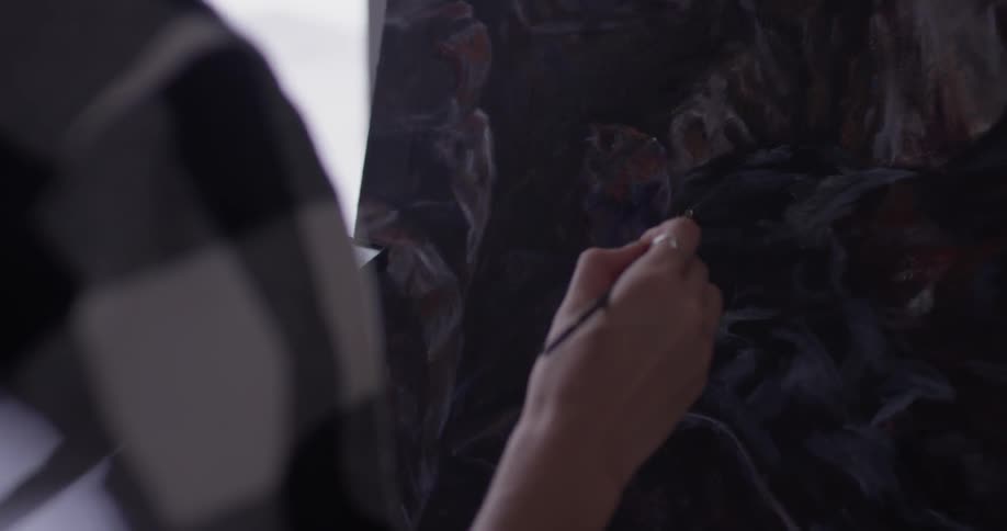 A woman painting on a canvas in a studio