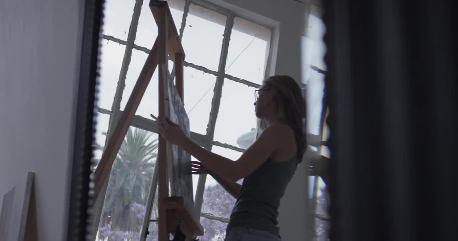 Woman setting a canvas on an easel