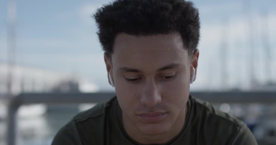 Man wearing wireless earbuds stares at camera and looks down