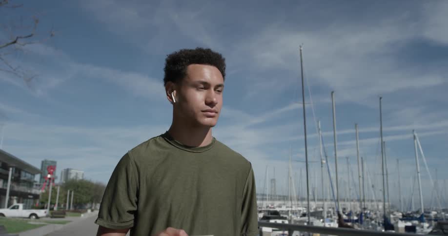 A man walking along the sea listening to music