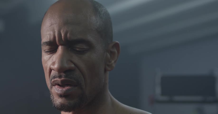 Man stands in a brightly lit room with his eyes closed