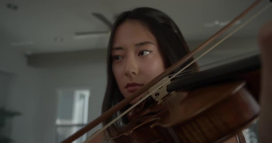 A woman playing a violin in a house