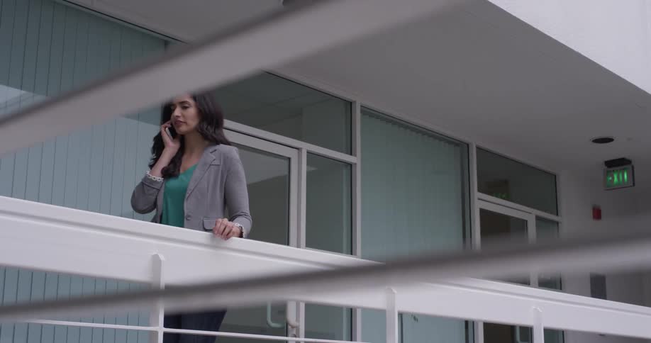 A woman talking on a phone on a balcony