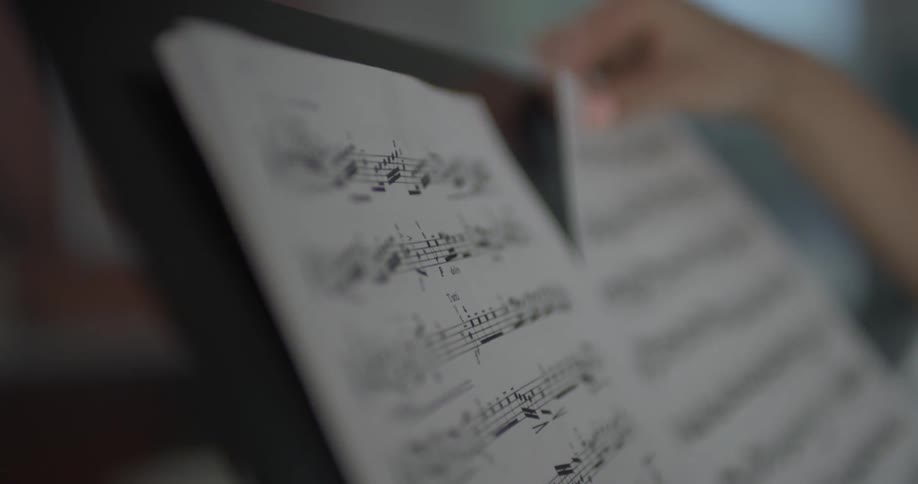 A person putting sheet music on a music stand