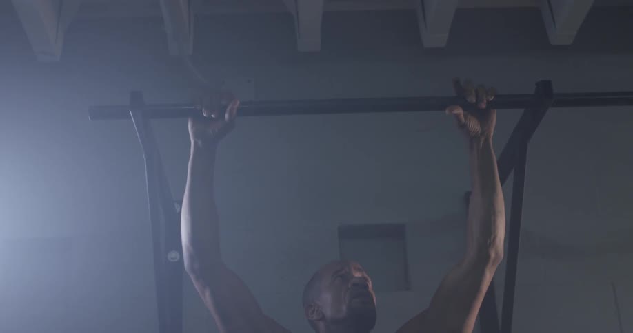 Man holds onto a bar above his head looking up