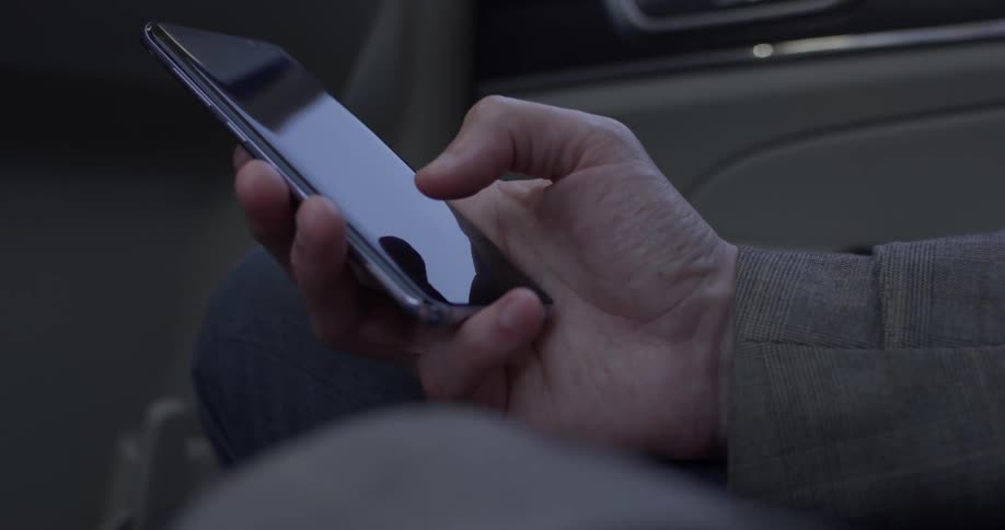 Person in car plays with cell phone