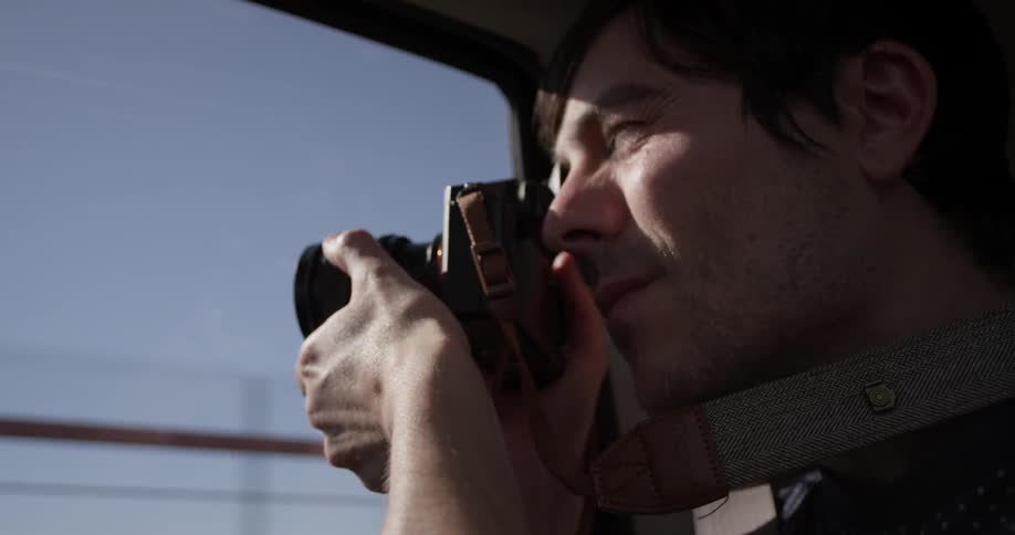 Man riding in passenger seat of car takes photos with camera