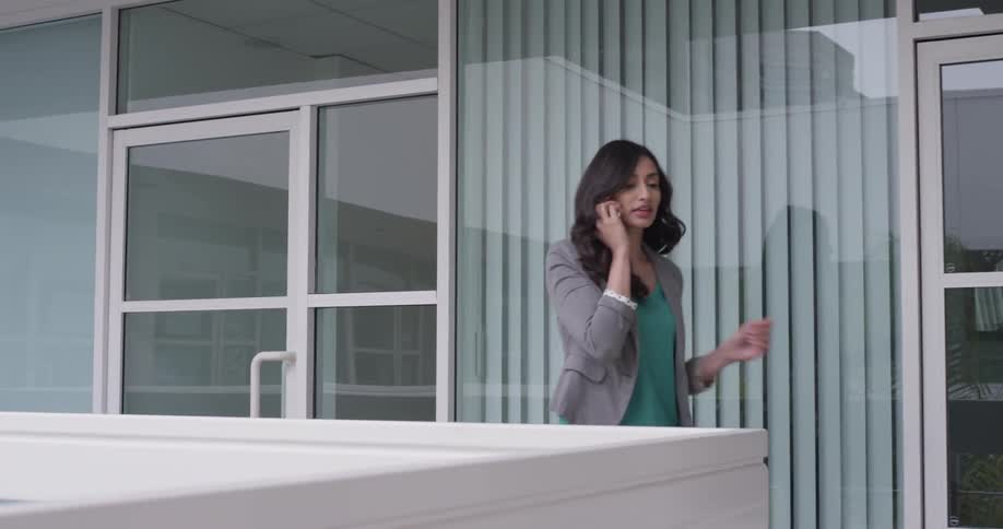 A woman walking on a balcony talking on her phone
