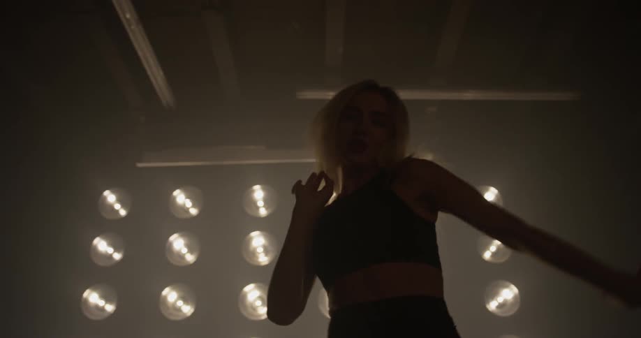A woman is dancing in front of a wall of lights