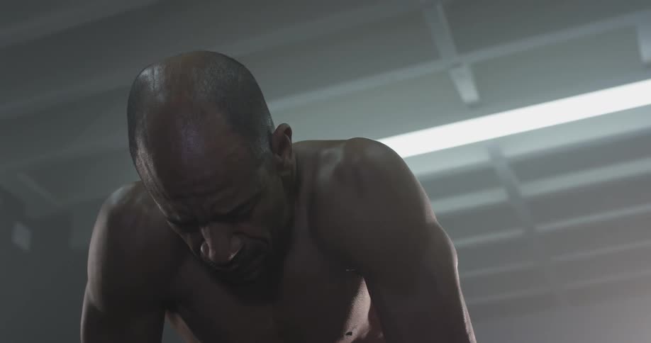 A man leaning over and looking down, then looks up with a tired look on his face