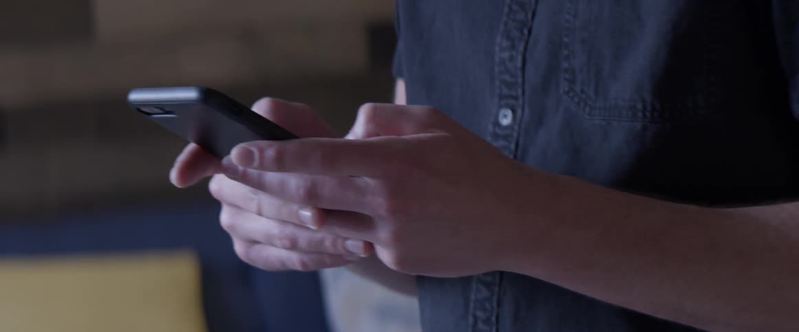 A man texting on a cell phone in a house