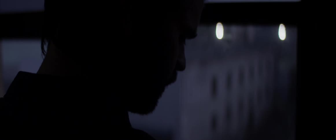 A man looking out a window at a city at night